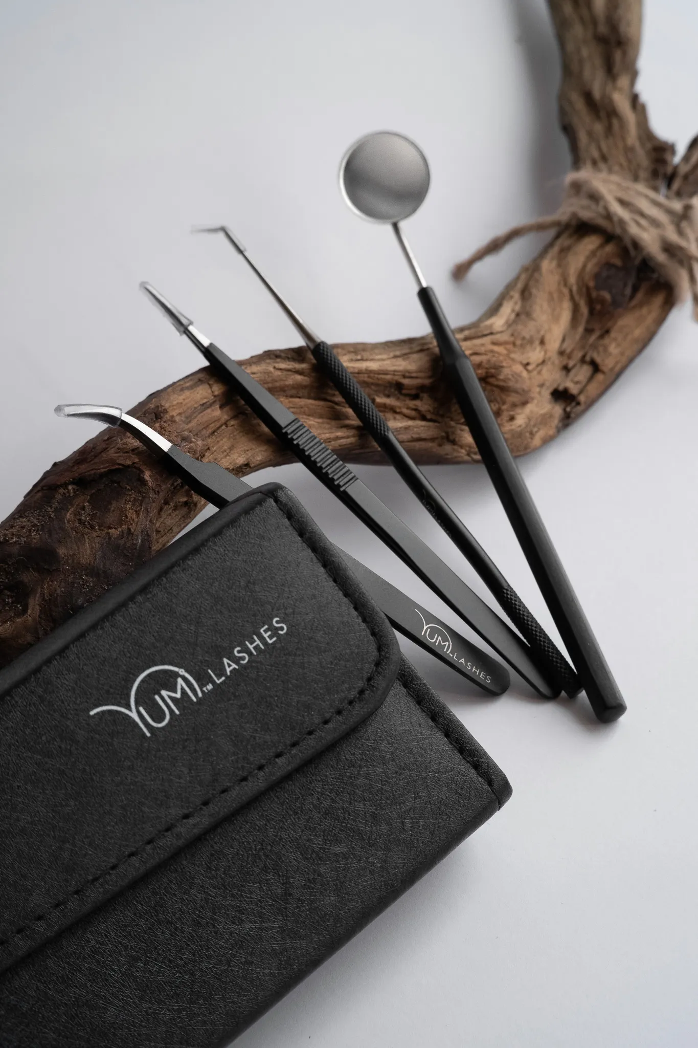 Предметна фотографія набору інструментів для вій YUM Lashes на світлому фоні з дерев'яним акцентом.
