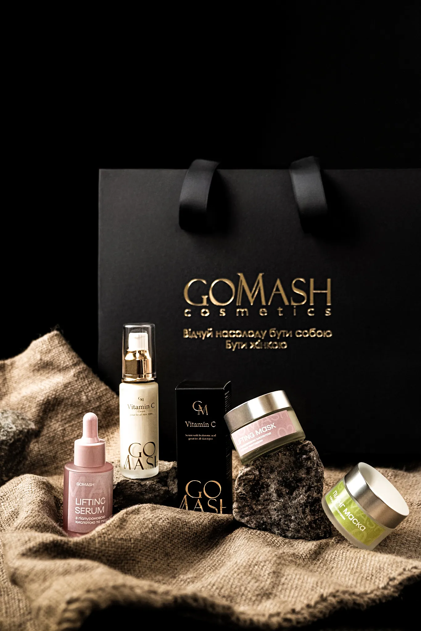 Предметна фотографія косметики GoMash: сироватка, крем Vitamin C, маски на текстурі тканини та каменях.