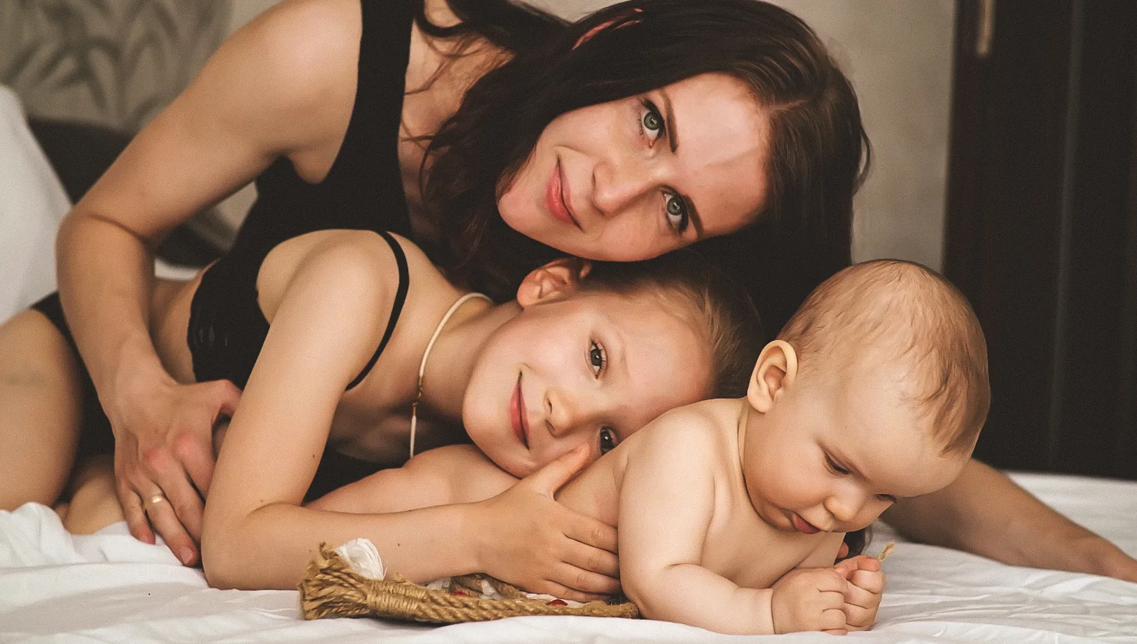 Фото щасливої сім'ї: мама з двома дітьми, граються на ліжку. Тематика Family, Children, Maternity.