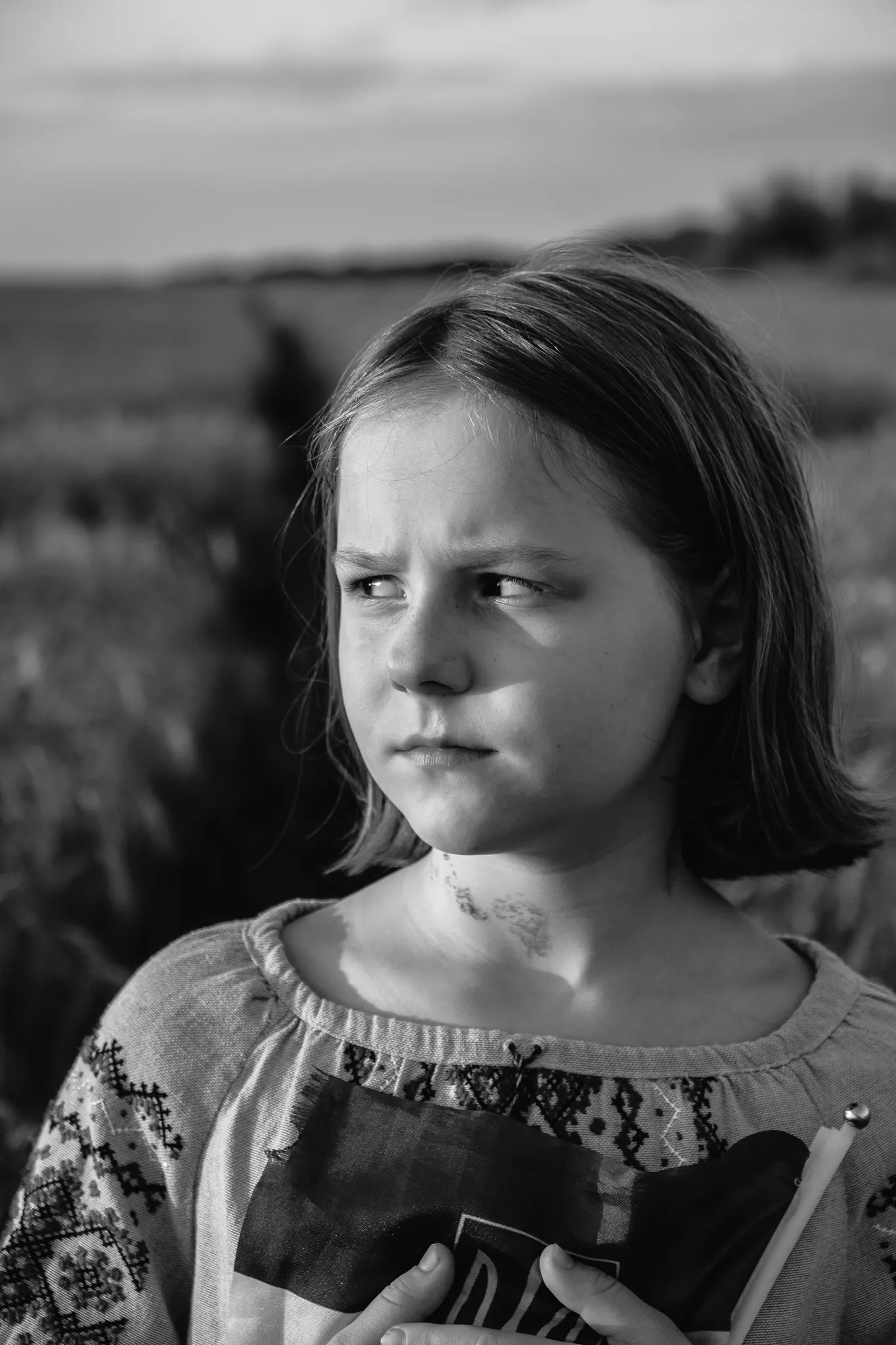 Чорно-біле фото дівчинки на фоні поля, портрет дитини, емоції, дитяча фотографія, сімейна фотосесія.