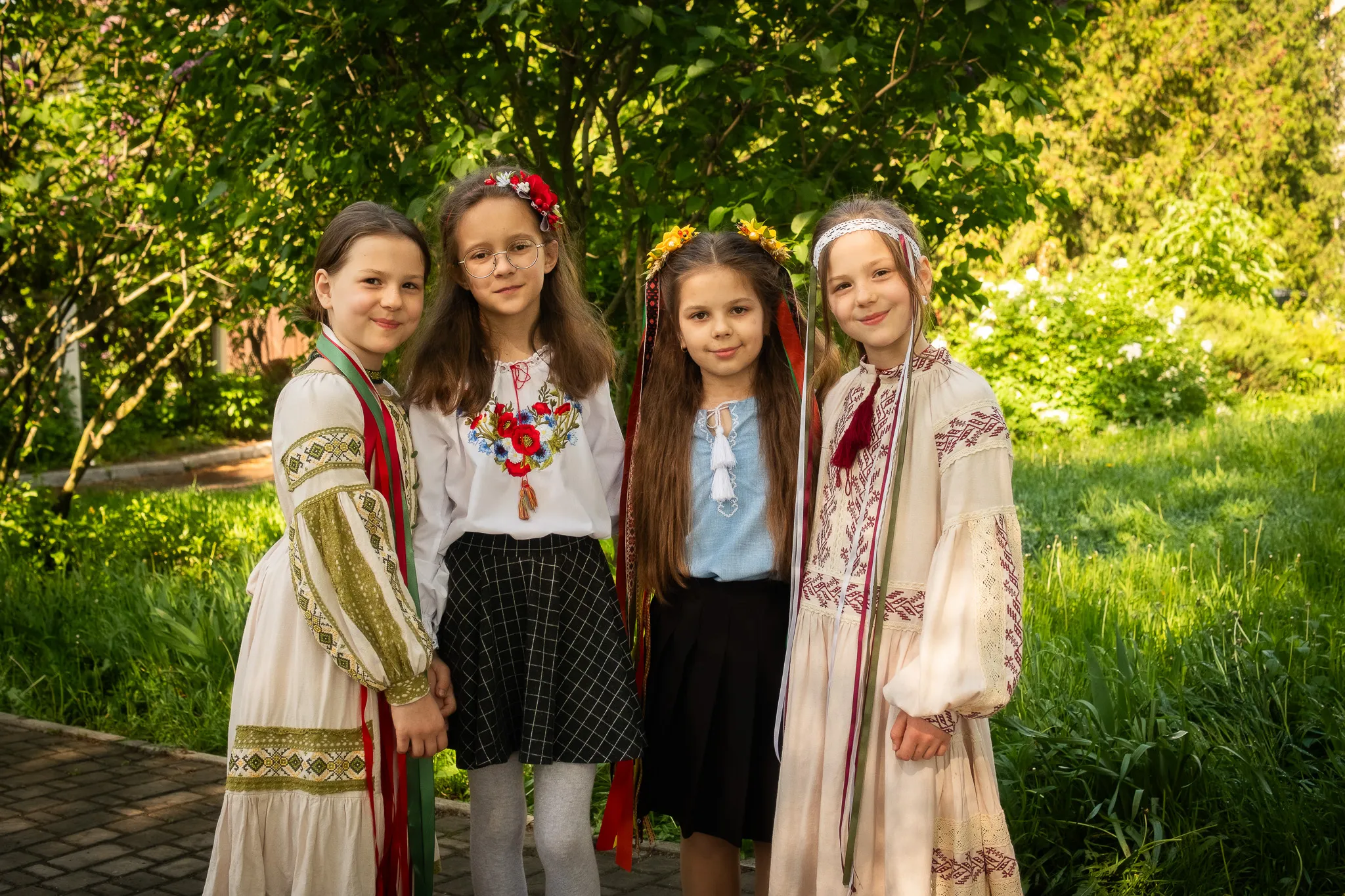 Чотири дівчинки в українських народних костюмах на фоні зелені. Сімейна атмосфера, діти, традиції.
