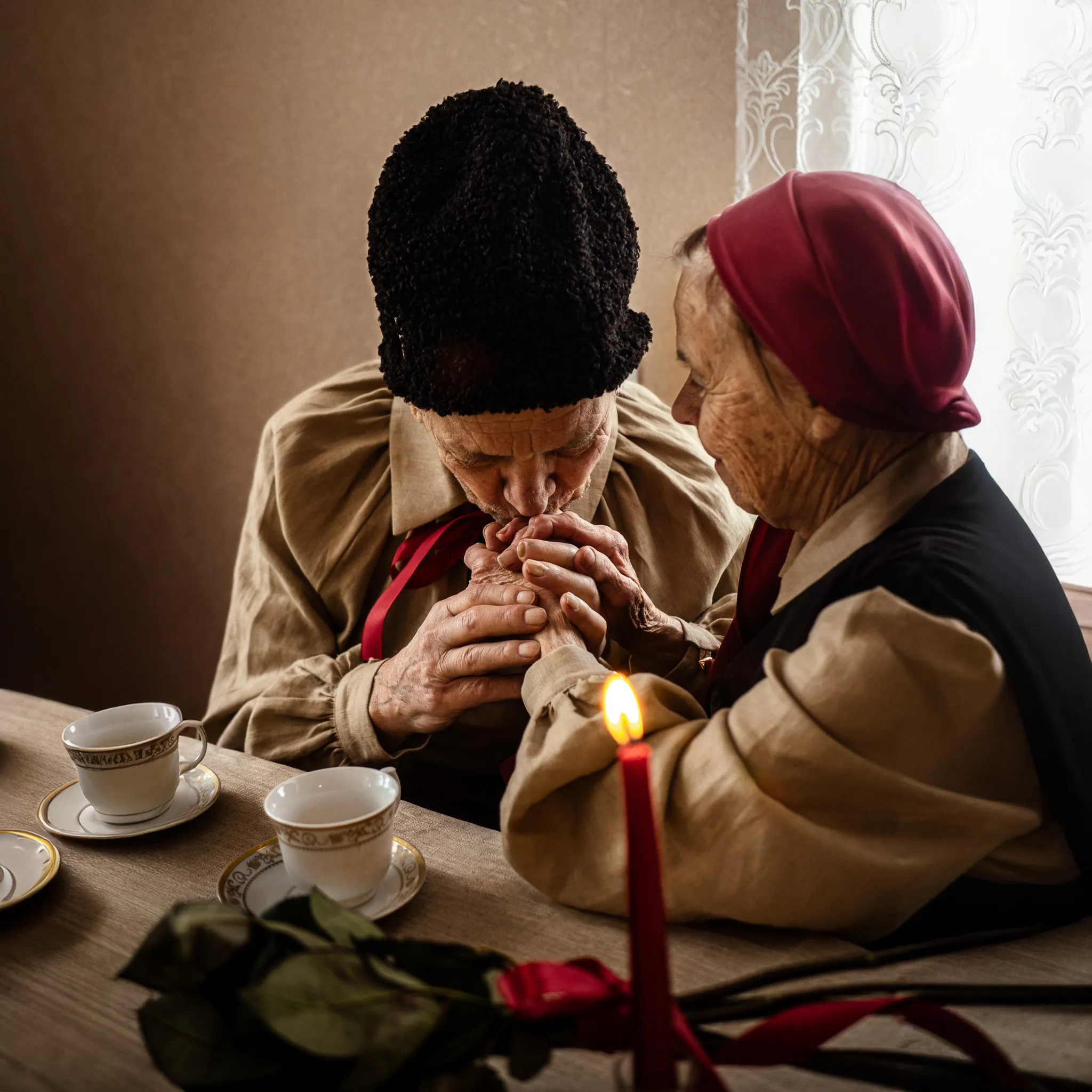 Двоє літніх людей у традиційному одязі тримаються за руки, тепла атмосфера, домашній затишок.